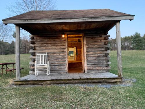 a wooden cabin with a chair in a field at Lake Lauderdale Campground in Cambridge