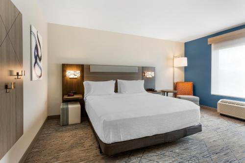 a bedroom with a white bed and a blue wall at Holiday Inn Express Belgrade-Bozeman Area by IHG in Belgrade