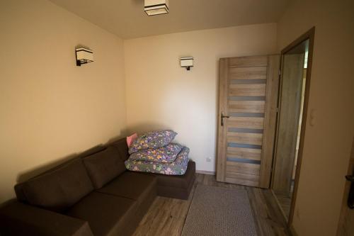 a living room with a brown couch and a door at Ostoja Niedźwiedzia in Cisna