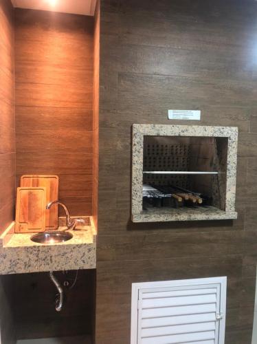 a kitchen with a sink and a counter with a fireplace at Apto familiar, 150mts do mar, completo e aconchegante em Palmas in Governador Celso Ramos