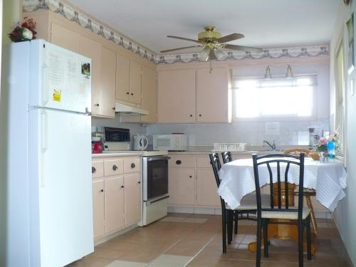 a kitchen with a white refrigerator and a table with chairs at Rainbow Bed & Breakfast in Niagara Falls