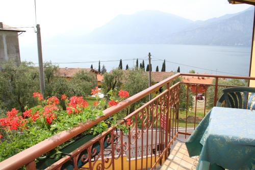 a balcony with red flowers and a view of the water at Hotel Casa Gagliardi in Brenzone sul Garda