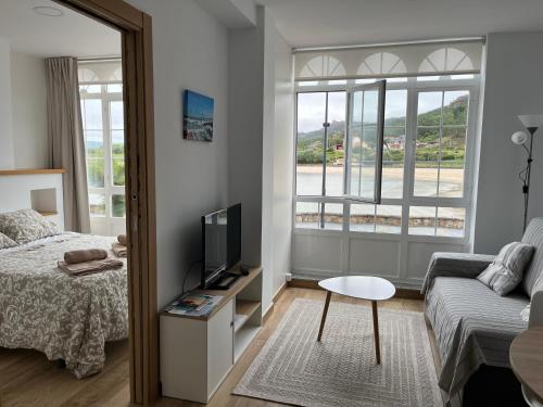 a bedroom with a bed and a tv and a couch at Apartamento paseo marítimo Camelle in Camelle