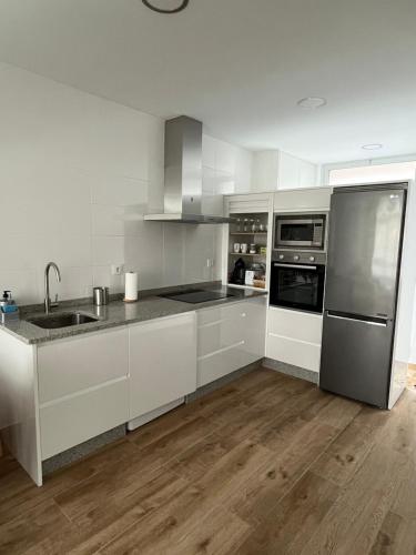 a kitchen with white cabinets and stainless steel appliances at Apartamento paseo marítimo Camelle in Camelle