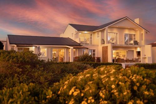 a house on the beach at sunset at Seapearl Oceanfront Villa and Cottage in Hermanus