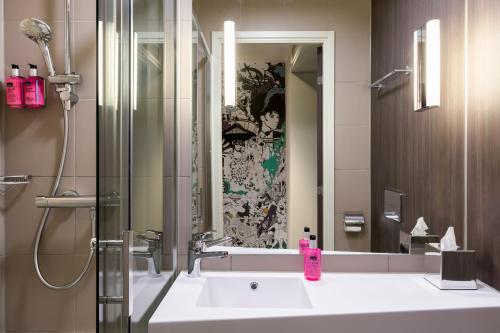 een badkamer met een wastafel en een spiegel bij Moxy Berlin Ostbahnhof in Berlijn