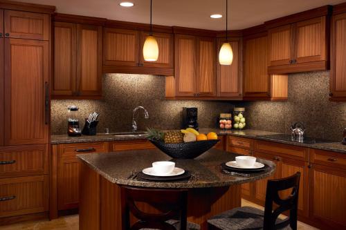 a kitchen with wooden cabinets and a island with a bowl of fruit at Koloa Landing Resort at Po'ipu, Autograph Collection in Koloa