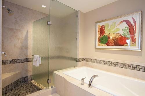 a bathroom with a tub and a glass shower at Koloa Landing Resort at Po'ipu, Autograph Collection in Koloa