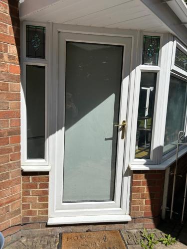 a glass door on a brick house with two windows at The Village apartment. in Marton