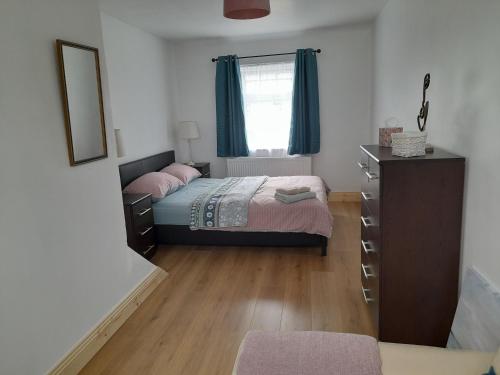 a bedroom with a bed and a dresser and a window at Central Town Apartment in Wexford