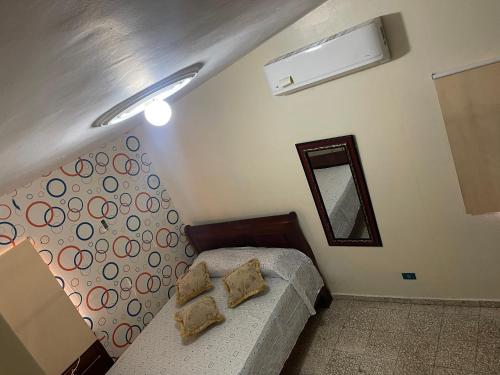 ein kleines Schlafzimmer mit einem Bett und einem Spiegel in der Unterkunft Residencial Parque del Este, Clásico Victoriano, 4-A in Los Tres Ojos de Agua