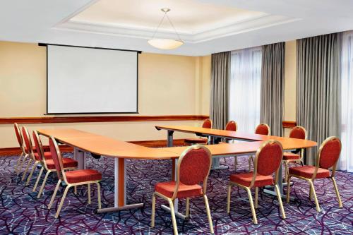 a conference room with tables and chairs and a whiteboard at Sheraton Skyline Hotel London Heathrow in Hillingdon