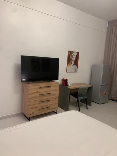a living room with a tv and a desk with a chair at CHEZ RIMA // Studio très chaleureux F1 // Très bien situé in Dakar