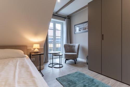 ein Schlafzimmer mit einem Bett und einem Stuhl und einem Fenster in der Unterkunft Summer Diek Ferienhaus Summerdiek 8 in Sankt Peter-Ording