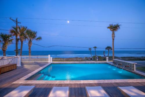 a swimming pool with a view of the ocean at Beachfront Pool Outdoor Kitchen Firepit Putting Green in Folly Beach