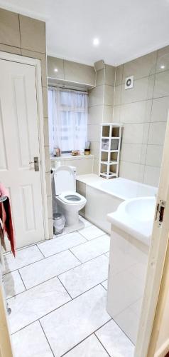 a bathroom with a toilet and a tub and a sink at Holiday Apartment in Abbey Wood