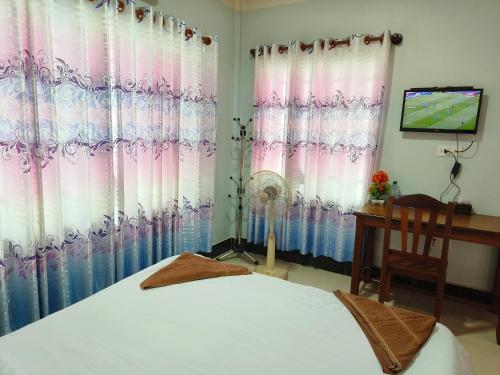 a bedroom with a bed and a desk and a television at Raksmey Kampuchea in Kampot