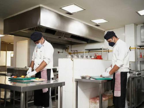 two chefs standing in a kitchen preparing food at Collection O 93572 HOTEL EXECUTIVE INN in Silchar