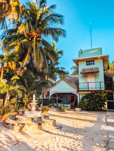 a house on the beach with a palm tree at Utopia Guesthouse & Yoga Studio beachfront home in El Cuyo