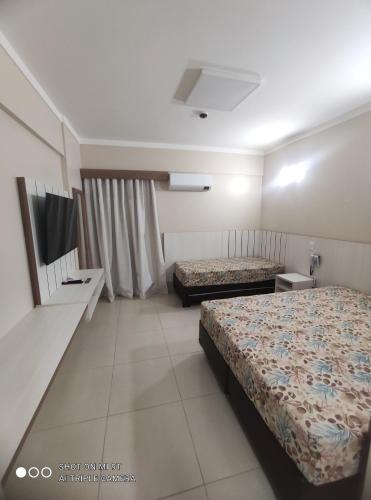a hotel room with two beds and a tv at Caldas Novas Spazzio Diroma com acesso ao Vulcao todos os dias in Caldas Novas