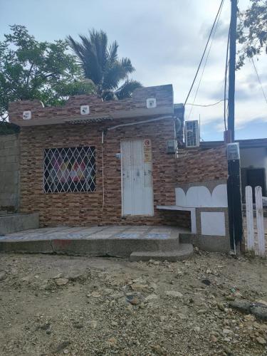 un edificio de ladrillo con una puerta blanca y una valla en Departamento Shaka en La Libertad