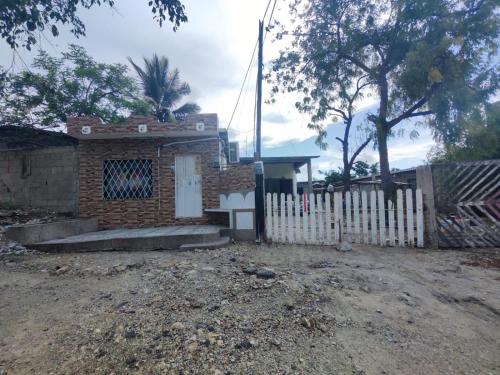 a small brick house with a white fence at Departamento Shaka in La Libertad
