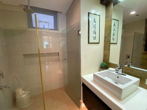 a bathroom with a sink and a shower and a mirror at PICO DE LORO ACCOMMODATIONS NORMAN AND LOURDES RESORT & CONDO PH in Nasugbu