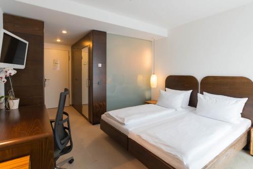 - une chambre avec un lit, un bureau et un ordinateur dans l'établissement ACHAT Hotel Corbin München Airport, à Freising