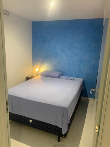 a bedroom with a large white bed with a blue wall at Aquarius Fortalezamar in Fortaleza