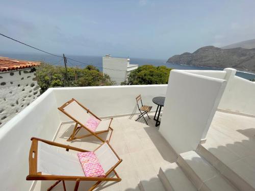 2 sillas y una mesa en un balcón con vistas al océano en Eden Gomera Suites, en Agulo