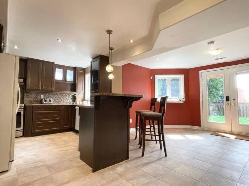 a kitchen with red walls and a bar with stools at Ella's Cozy Retreat at Richmond Hill in Richmond Hill