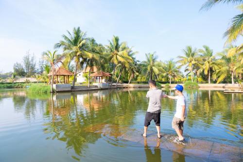 a man and a boy standing in the water at Kega Lighthouse Resort Bình Thuận in Ke Ga