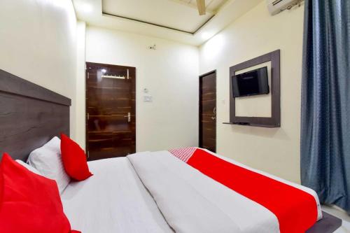 1 dormitorio con 1 cama con almohadas rojas y TV en OYO Flagship Hotel Pink Orchid en Kota