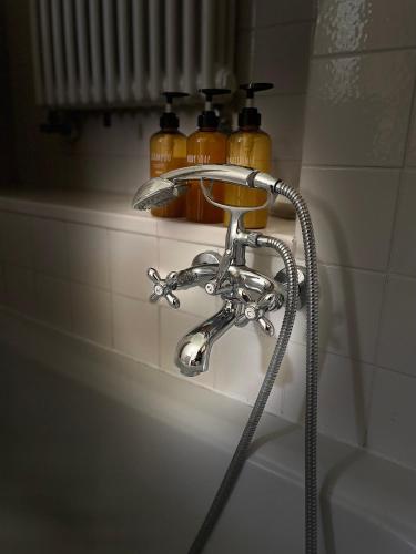 a bathroom sink with a shower faucet and two bottles at Dimora Storica La Corte Delle 4 Stagioni in Ozzano Monferrato
