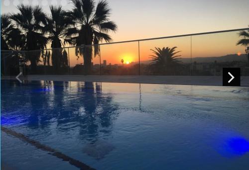 a swimming pool with palm trees and the sunset at LUXURY LA PENTHOUSE PRIME LOCATION Min from HOLLYWOOD and DOWNTOWN in Los Angeles