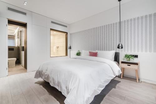 a white bedroom with a large bed and a bathroom at Stey Beijing Sanlitun Boutique Hotel in Beijing