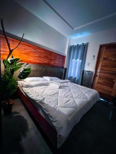 a bedroom with a large bed with a wooden headboard at M-Resort Siargao in General Luna