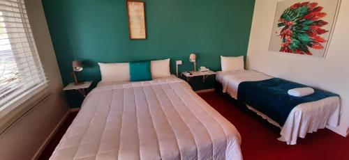 um quarto com duas camas e duas mesas com candeeiros em Karuah Gardens Motel em Karuah