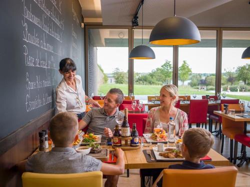 een groep mensen aan een tafel in een restaurant bij Landal Village Leau Dheure in Froid-Chapelle