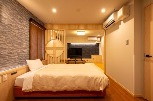 a bedroom with a bed and a flat screen tv at Bell's Inn Tsuchiura in Tsuchiura