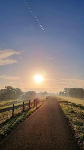 a road leading into a field with the sun in the distance at Hasenbau Flüren in Wesel