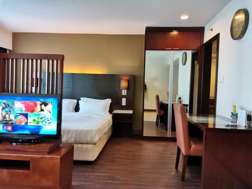 a hotel room with a bed and a desk with a television at Greenage MingSuite 明绿时代套房 Kota Kinabalu 亚庇市中心 in Kota Kinabalu