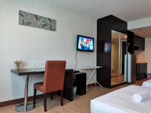 a hotel room with a desk and a tv on the wall at Greenage MingSuite 明绿时代套房 Kota Kinabalu 亚庇市中心 in Kota Kinabalu