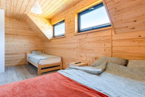 a log cabin with a bed and two windows at OSADA JANTAR 2 in Jantar