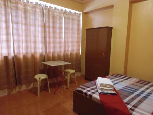 a bedroom with a bed and a table and two stools at JAZ-M Pensionhouse in Tagbilaran City