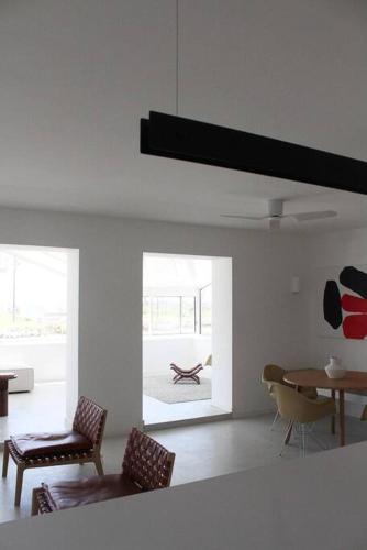 a living room with chairs and a table and a room with a table at Mimizan Blue - Laid back luxury on the beach in Mimizan