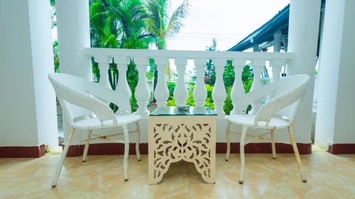 a table with two chairs and a table with a vase on it at Lillywoods NV Beach Resort in Calangute