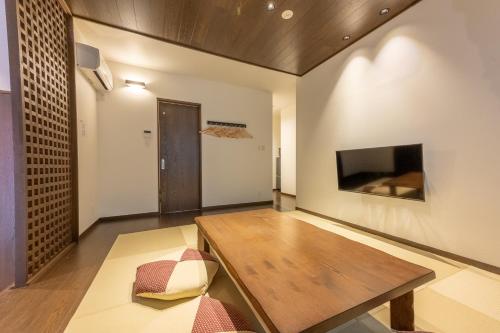 a living room with a wooden table and a tv at Irodori Hotel DAIDAI in Fukuoka