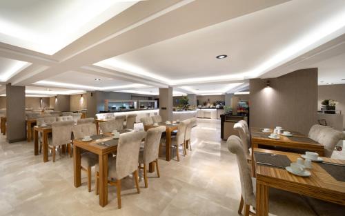 a restaurant with wooden tables and chairs and a kitchen at Orka Royal Hotel & Spa in Istanbul
