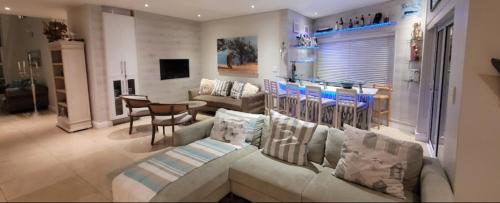 a living room with a couch and a table at Gull on the Bay Boutique Guest House in Bloubergstrand